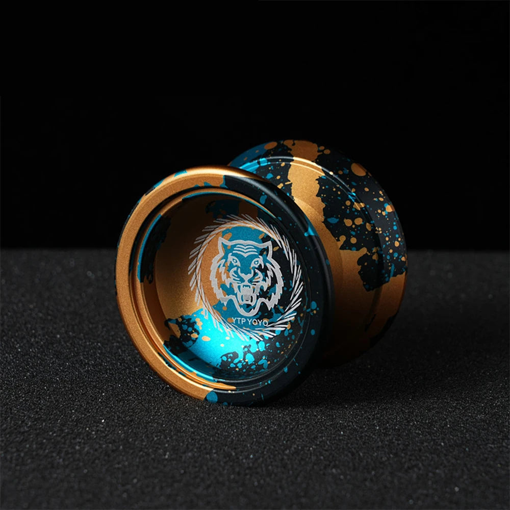 A close-up of a professional aluminum alloy yo-yo with a gold and blue design featuring a tiger head.