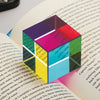 A colorful optical color cube prism resting on an open book page.