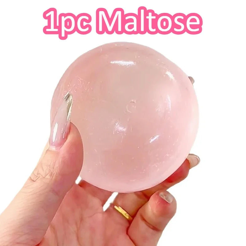 A hand holds a pink maltose squishy stress relief toy.