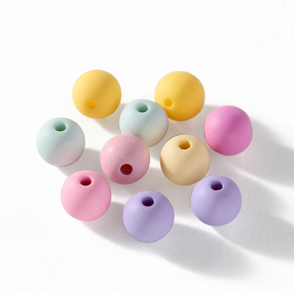 A collection of round matte acrylic beads in various pastel colors including yellow, mint green, pink, and purple.