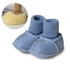 Pair of blue suede baby booties with plush fur lining shown next to a small brown boot.
