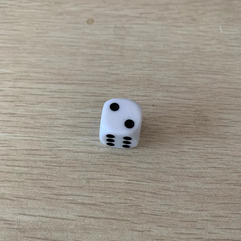 A single white die with five pips is shown on a light wooden surface.