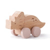 A wooden dinosaur toy car with pink wheels and features on its body.