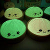 A close-up of several soft sensory squishy dumpling toys glowing with green light.