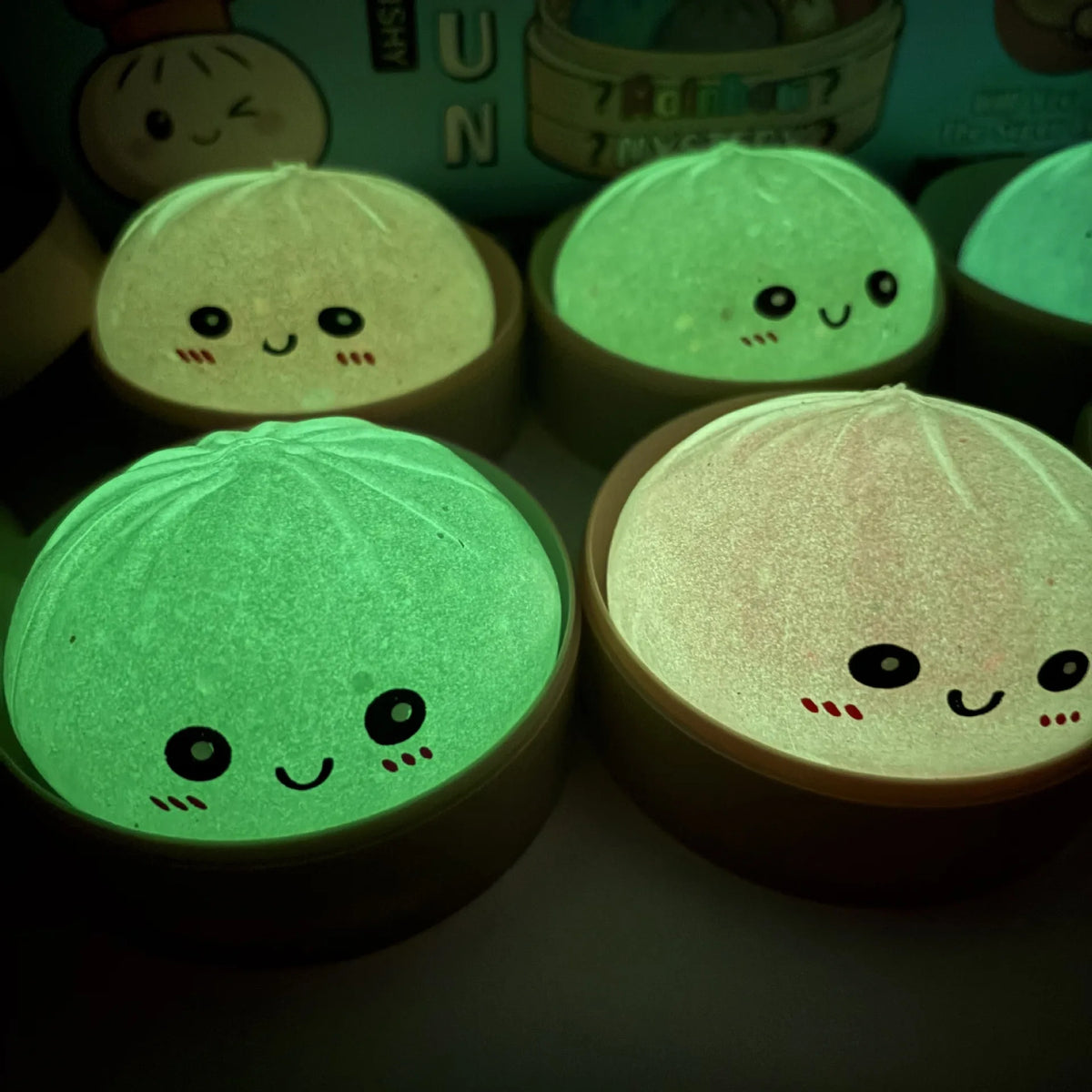 A close-up of several soft sensory squishy dumpling toys glowing with green light.