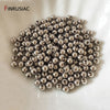 A pile of small, round, silver-colored spacer beads for jewelry making on a white surface.