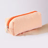 An orange and white striped canvas pencil case with a zipper is held in a hand.