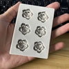 A silicone mold with five rose flower shapes for candle and soap making is held in a hand.