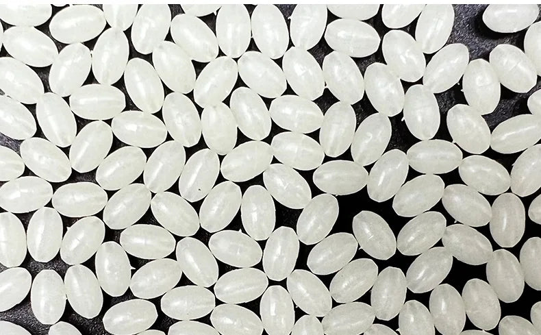 A close-up view of numerous small, translucent white luminous fishing beads for sea and river lures.