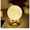 A glowing moon-shaped night light illuminates a wooden surface.