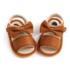 Pair of tan leather baby summer sandals with bowknot detail and soft anti-slip sole