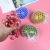 A hand holds several colorful squeeze stress relief balls, including blue and red ones with mesh netting.