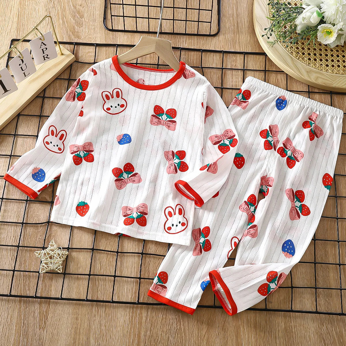 White long sleeve cotton pajama set for kids featuring a pattern of rabbits and strawberries.