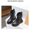 A pair of black Movement shoes, ankle boots with laces and a rubber sole, displayed on a white surface.