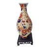A ceramic flower vase with a mottled orange and blue floral pattern displayed on a dark wooden stand.