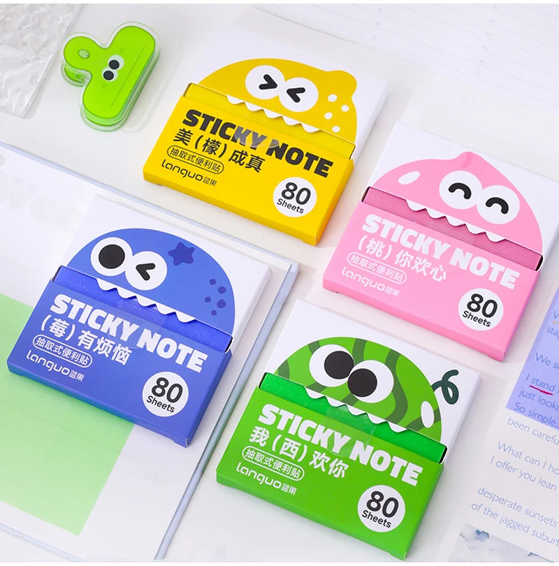 A collection of yellow and pink sticky notes with cute designs, including a pull-through dispenser.