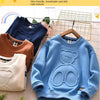 A light blue cartoon bear pullover sweatshirt displayed on a wooden hanger with other colored sweatshirts in the background.