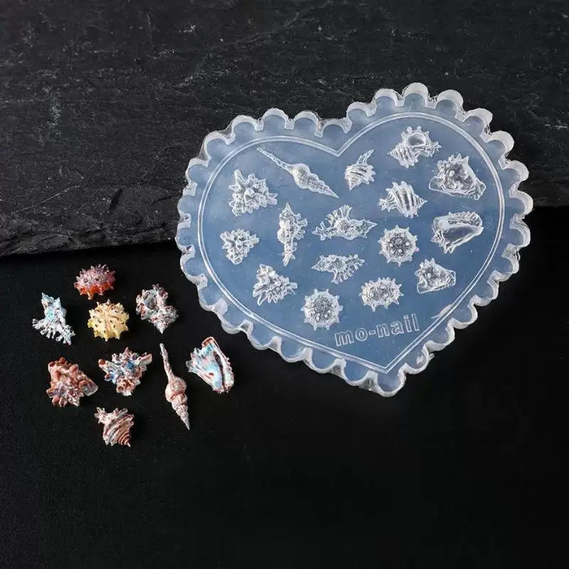 A heart-shaped silicone mold featuring intricate sea shell, starfish, and ocean designs for nail art.