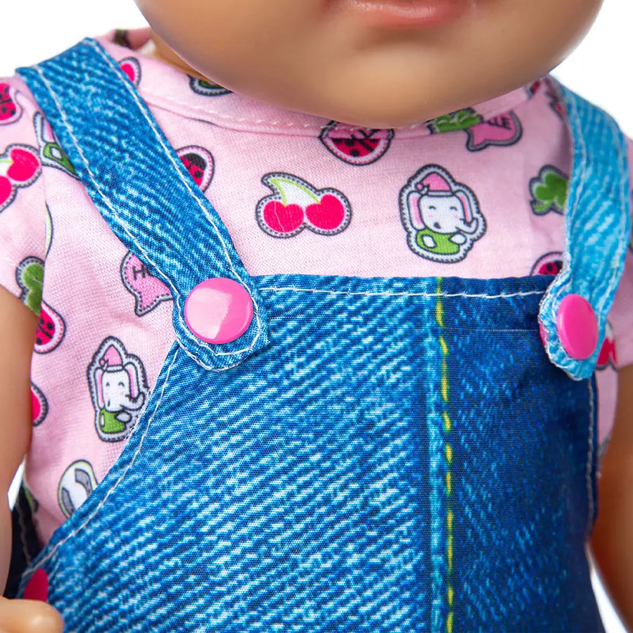 A baby doll wearing a pink shirt with a cat print and a blue denim overalls.