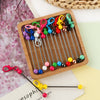 A wooden tray holds various metal keychain bars with lobster clasps in colorful and silver tones for DIY jewelry making.