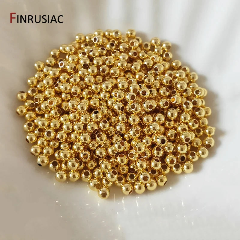 A pile of small, round gold-plated brass spacer beads for jewelry making.