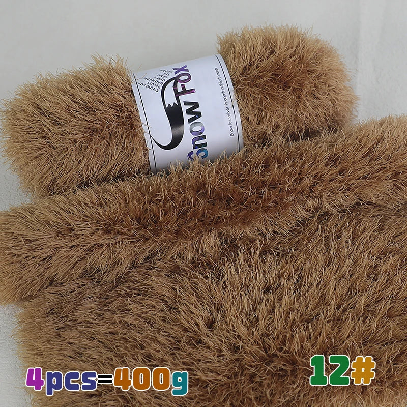 A roll of black and white yarn labeled Snow Fox is placed on a pile of brown faux fur yarn.