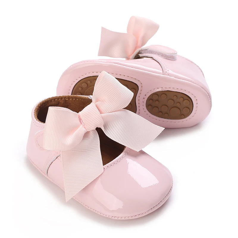 Pink lace-trimmed baby girl moccasin shoes with a pink bow