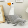 A white and gray shark plush toy with an orange snout sitting on a white surface.