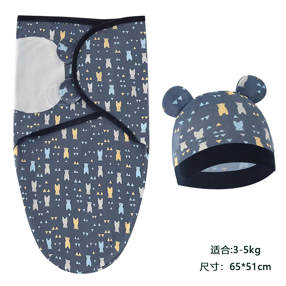 A navy blue cotton newborn swaddle blanket and hat set featuring a pattern of yellow and blue cats.