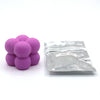 A pile of purple candle dye chips for soy wax, beeswax, and paraffin wax is shown next to a sealed plastic bag.