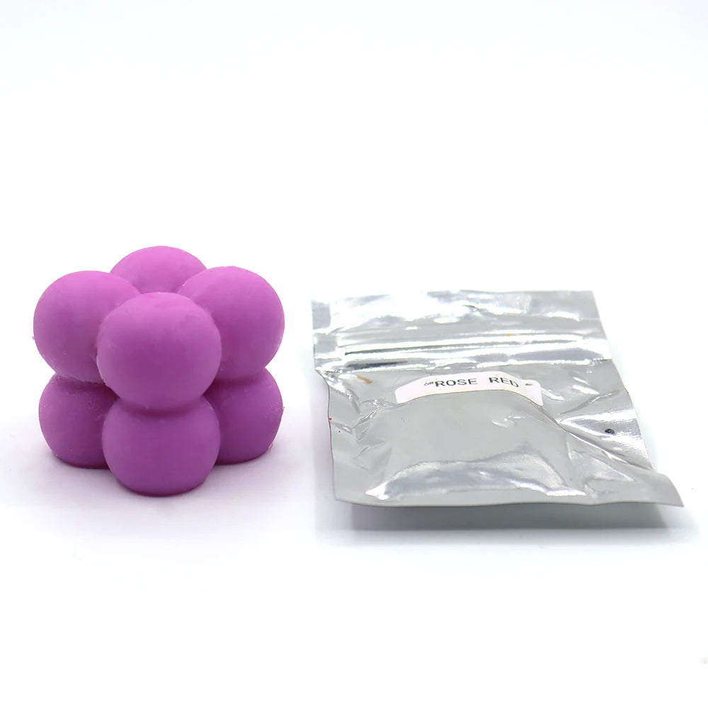 A pile of purple candle dye chips for soy wax, beeswax, and paraffin wax is shown next to a sealed plastic bag.