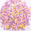 A pile of colorful polymer clay flower charms in various shades of pink, purple, and yellow.