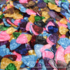 A close-up view of a 10-pack of assorted colored celluloid guitar picks scattered on a white surface.