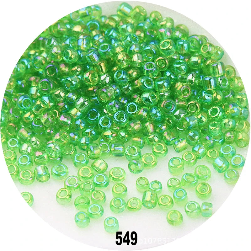 A pile of colorful round loose glass seed beads in various shades of green and yellow-green.