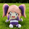 A pink and purple plush toy doll with large eyes sitting on green grass.