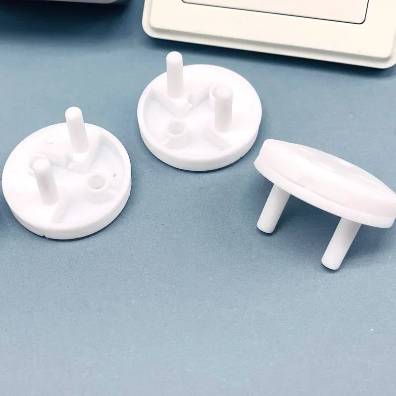 A collection of white rotating socket safety covers for baby proofing are displayed on a light blue surface.