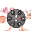 Hands are operating an electric shock party game device with six fingers placed on the surface.