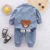 A light blue corduroy tracksuit set for a child featuring a bear graphic and matching shoes.