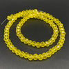 A strand of yellow Austrian faceted crystal beads for jewelry making laid out on a dark surface.