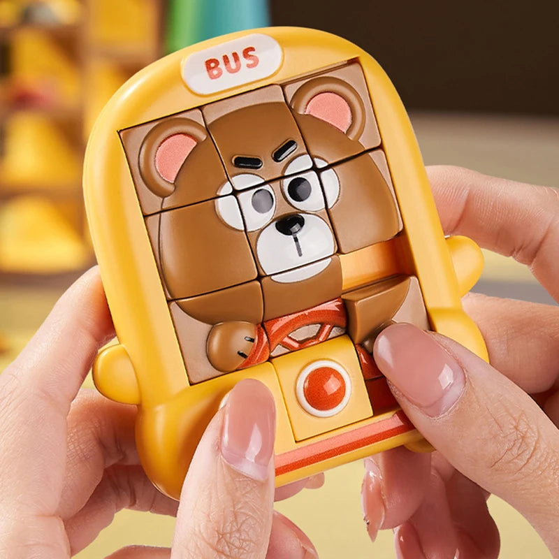 A hand holds a yellow animal slide puzzle featuring a brown bear and an orange bus design.