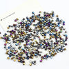 A scatter of iridescent electroplated crystal glass beads in various shades of blue, purple, and gold.
