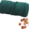 A spool of dark green natural cotton macrame rope next to several dried natural seed pods.