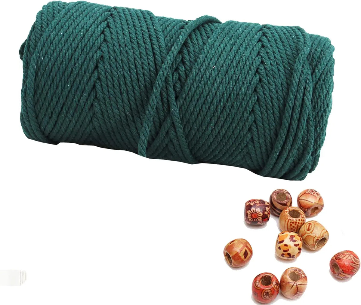 A spool of dark green natural cotton macrame rope next to several dried natural seed pods.