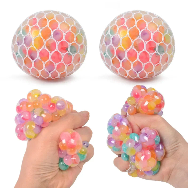 A hand holds a rainbow squishy stress relief ball, showing its colorful, translucent texture.