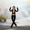 A plush doll resembling Elvis Presley with black attire and gold accents standing on a snowy surface.
