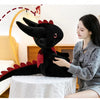 A young woman is holding a black Toothless Dragon plush toy, which is a soft cuddly stuffed animal.