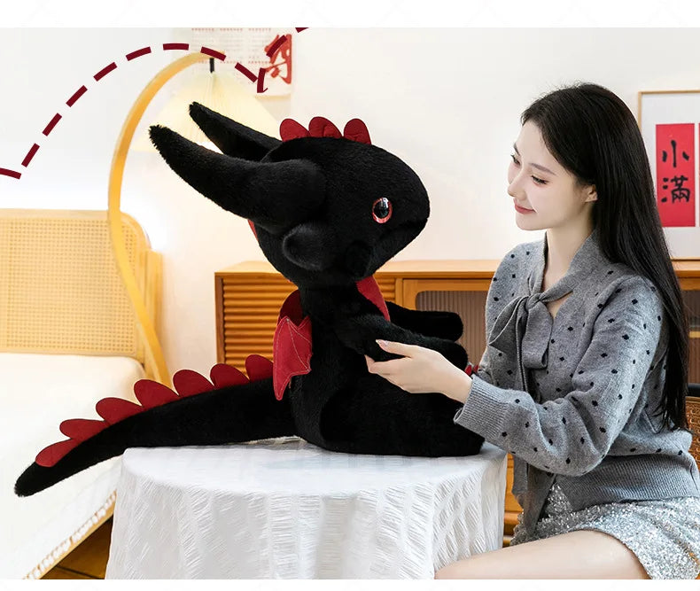 A young woman is holding a black Toothless Dragon plush toy, which is a soft cuddly stuffed animal.