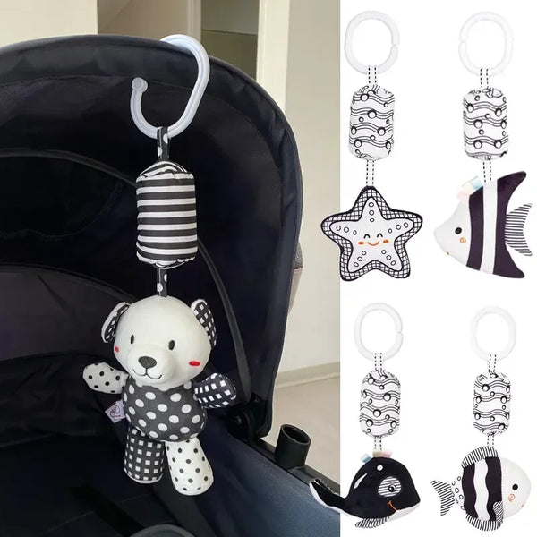 A black baby carrier features an infant rattle shaped like a white bear with black polka dots.