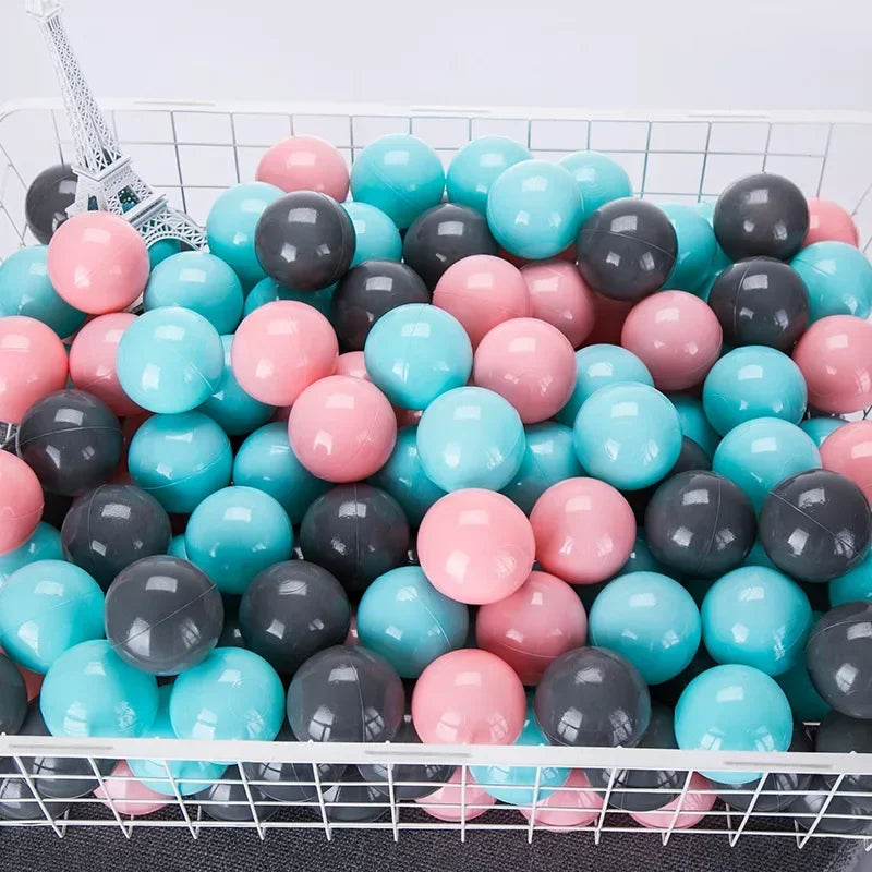 A collection of colorful plastic play balls in various shades of pink, blue, and gray are displayed in a white wire basket.