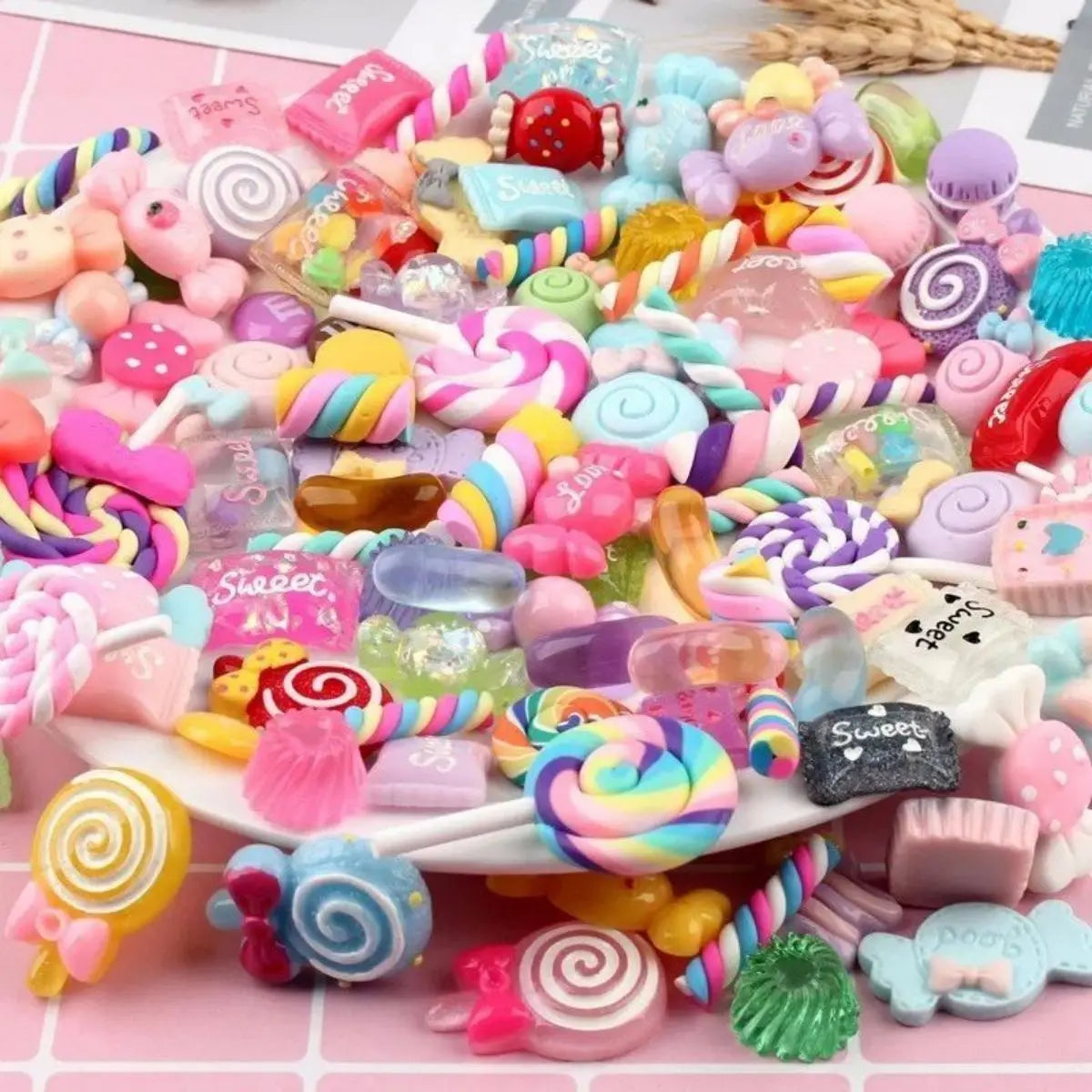 A colorful assortment of resin sweets and charms for DIY crafting, including various pink, purple, and yellow candies.